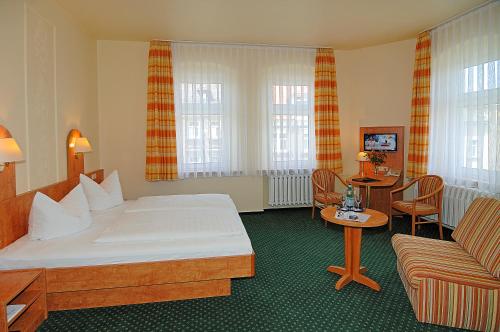 pokój hotelowy z łóżkiem i kanapą w obiekcie Hotel Stadt Löbau w mieście Löbau