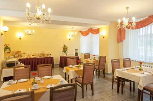 Hotel Stadt Löbau في لوباو: غرفة طعام مع طاولات وكراسي وثريات