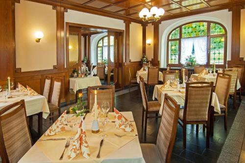 a restaurant with white tables and chairs and windows at Hotel Stadt Löbau in Löbau