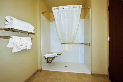 a bathroom with a shower with a curtain and towels at Cobblestone Inn & Suites - Avoca in Avoca