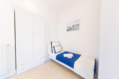 a white bedroom with a bed with blue and white sheets at Villa Fortuna Holiday Resort in Ischia