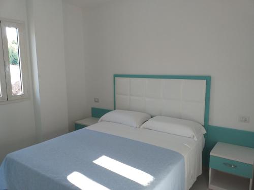 1 dormitorio con 1 cama con manta azul y ventana en appartamenti baia di peschici en Peschici