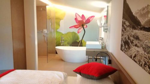 a bathroom with a bath tub and a flower on the wall at Vital & Sporthotel Brixen in Brixen im Thale