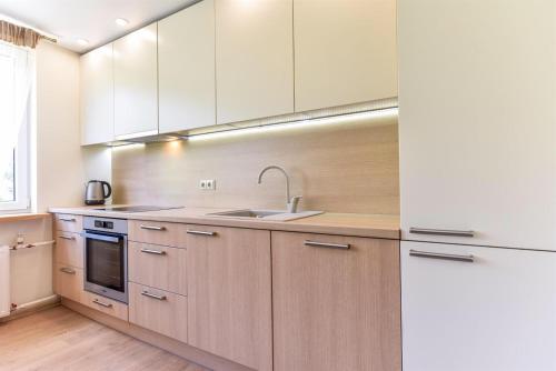 Una cocina con gabinetes blancos y un fregadero. en Crystal Apartment, en Druskininkai