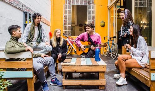 a group of people sitting on benches playing music at Play Hostel Arcos in Buenos Aires