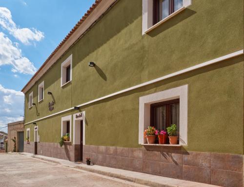 a green building with two windows with potted plants at Morada 2 in Casas del Cerro