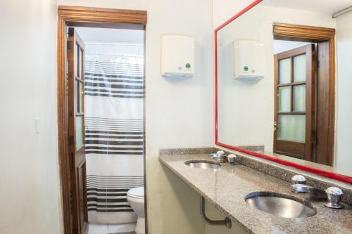 a bathroom with two sinks and a toilet and a mirror at Play Hostel Arcos in Buenos Aires
