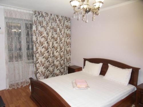 a bedroom with a bed and a chandelier at Карасай Батыра 108 in Almaty
