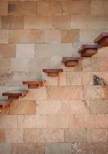 a stone wall with wooden stairs in a building at Herradura Hotel Suites in Neuquén