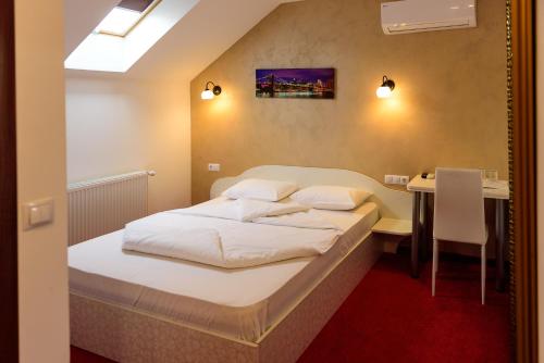 a small bedroom with a bed and a table at Equinoxe Royal Reghin in Reghin