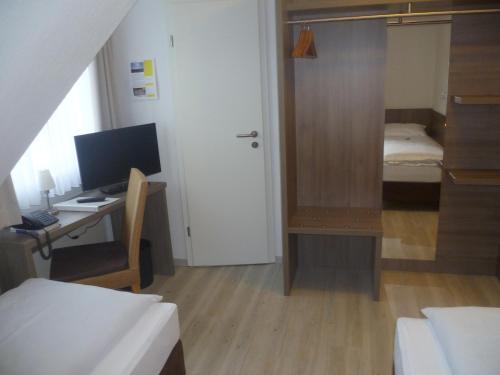 a room with a desk with a computer and a bedroom at Landgasthof Zur scharfen Ecke in Hildesheim