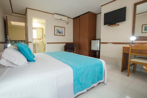 a hotel room with a large bed and a desk at Hotel Principe in Tuluá