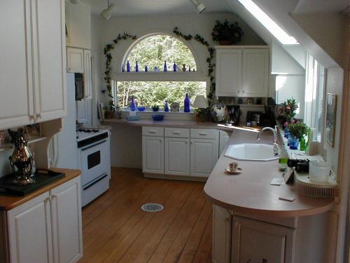 a kitchen with white cabinets and a sink and a window at Mountain Valley Retreat in Killington