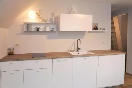 una cocina con armarios blancos y fregadero en Apartments Alteri Domi en Bohinj