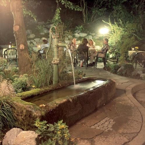a fountain in a garden with people sitting at tables at Hotel 3 Könige in Oberwolfach