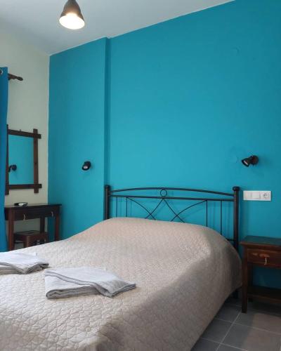 a bedroom with a bed with a blue wall at Sokaki rooms in Skiathos