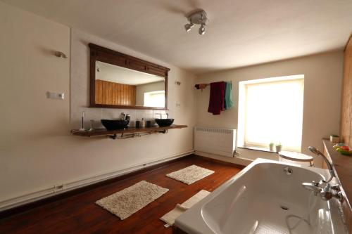 a bathroom with a bath tub and a mirror at La ferme de Bertogne in Bertogne