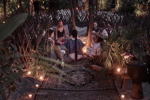 a group of people sitting on a porch with lights at Nômade Temple Tulum in Tulum