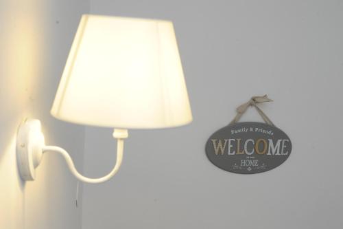a white lamp with a welcome sign on it at Aduepassi apartments in Manfredonia