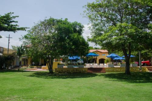 a park with trees and tables and blue umbrellas at Porto Bello Hotel Boutique in Puerto Colombia