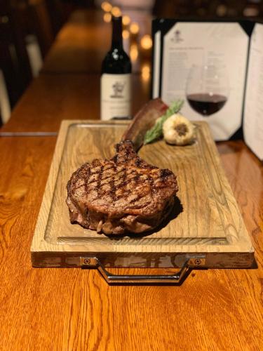 a steak on a cutting board with a glass of wine at Hotel Mission De Oro in Santa Nella Village