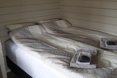 Una cama blanca con dos toallas encima. en Hvammur 3 Hrakhólar with private hot tub, en Kaldrananes