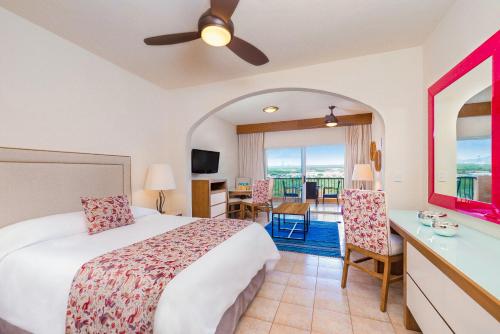 a hotel room with a bed and a table and chairs at Villa del Palmar Beach Resort & Spa in Cabo San Lucas