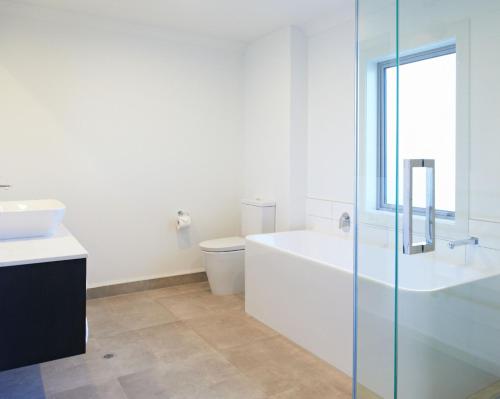 a bathroom with a tub and a toilet and a sink at Kelly Rd Cambridge Lodge in Cambridge