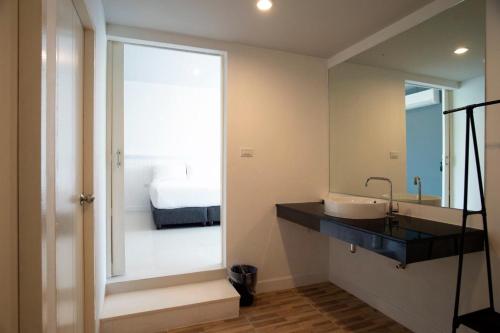 a bathroom with a sink and a mirror and a bed at BHIVE in Nakhon Phanom