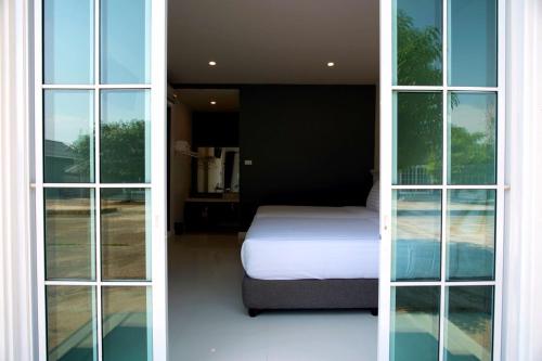 a bedroom with a bed and large windows at BHIVE in Nakhon Phanom