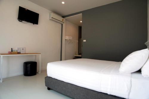 a bedroom with a white bed and a tv on the wall at BHIVE in Nakhon Phanom