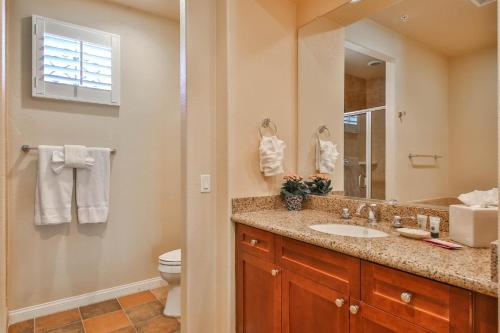een badkamer met een wastafel, een toilet en een spiegel bij H90 Single Story Townhome Near Beautiful Fountain Condo in La Quinta