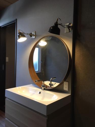 a bathroom with a sink with a mirror and lights at 南紀くまのいえ-WAKAYAMA・古座- in Kushimoto