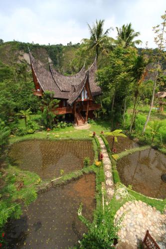 a building with a roof in the middle of a garden at Padi Ecolodge in Bukittinggi