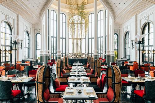 a dining room with tables and chairs and windows at Hotel de la Coupole - MGallery in Sa Pa