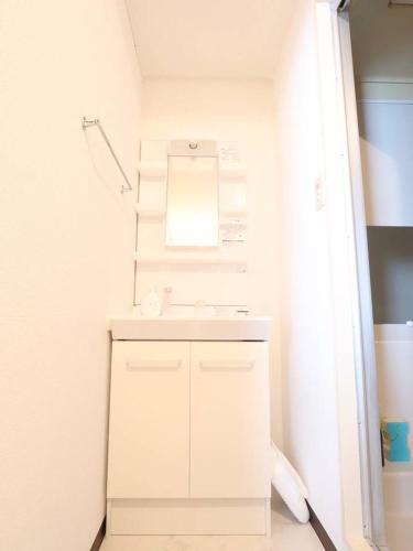 a white bathroom with a sink and a mirror at 湘南茅ヶ崎/湘南ライフの楽しめるアパートメント in Chigasaki
