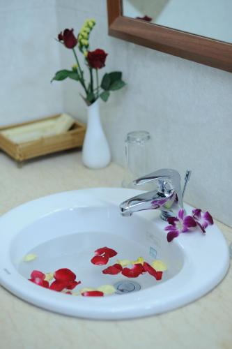 a white bathroom sink with flower petals on it at Hoang Yen Hotel in Thuan An
