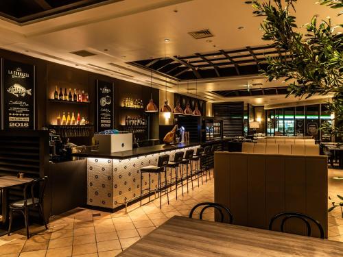 a bar in a restaurant with tables and chairs at HOTEL MYSTAYS Matsuyama in Matsuyama