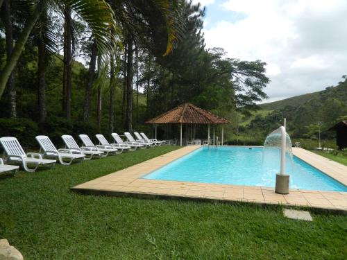 a swimming pool with lounge chairs and a gazebo at Fazenda Hotel Alvorada in Santos Dumont