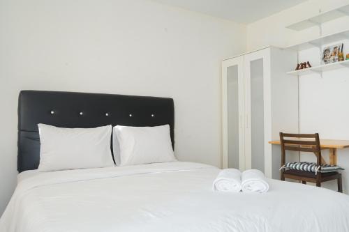 - une chambre avec un lit doté de draps blancs et d'une chaise dans l'établissement Homey Studio Apartment at Margonda Residence 3 By Travelio, à Depok
