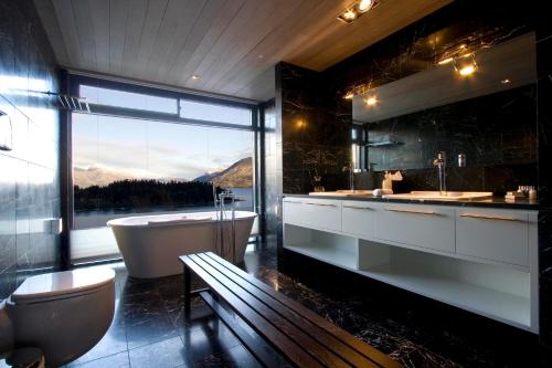 a bathroom with a tub and a toilet and a bath tub at Forty Two by Amazing Accom in Queenstown