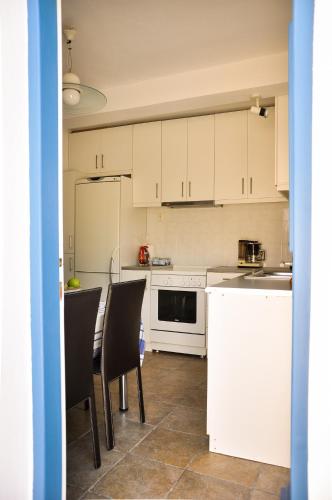 a kitchen with white cabinets and a table and chairs at Elena's Guest House in Aegina Town