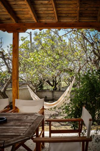 a hammock on a patio with a table and chairs at Elena's Guest House in Aegina Town