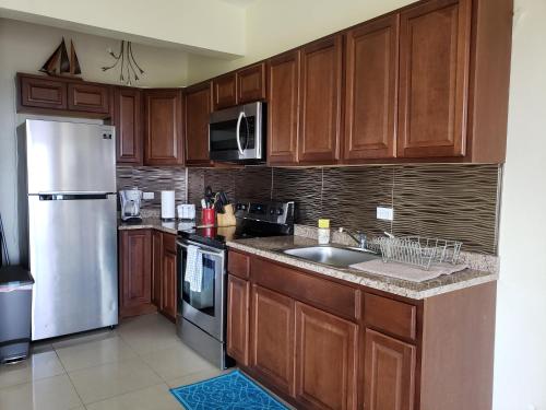 a kitchen with wooden cabinets and a stainless steel refrigerator at Villa Indigo Sunny 1BR Apartment in Private Gated Estate in Charlotte Amalie