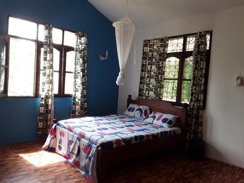 een slaapkamer met een bed met blauwe muren en ramen bij Akogo House - Hostel and Backpackers in Mombasa