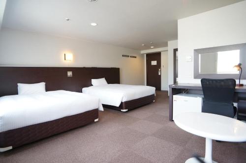 een hotelkamer met 2 bedden en een bureau bij Green Rich Hotel Kagoshima Tenmonkan in Kagoshima