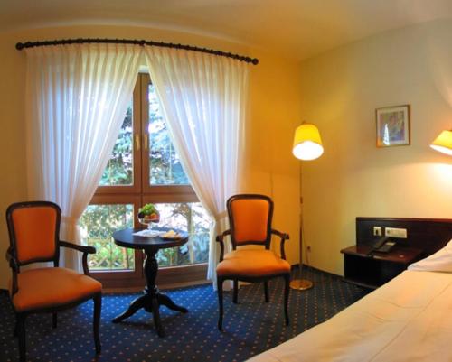 HügelsheimにあるHotel Waldhausのベッド1台、椅子2脚、テーブルが備わる客室です。