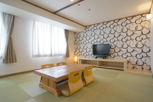 a dining room with a table and a tv on a wall at Green Rich Hotel Kagoshima Tenmonkan in Kagoshima