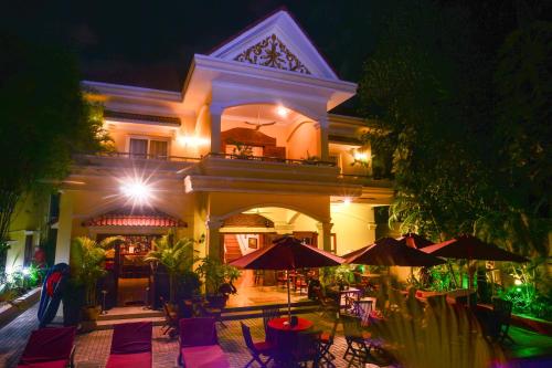 ein Gebäude mit einer Terrasse mit Tischen und Sonnenschirmen in der Nacht in der Unterkunft Villa Grange in Phnom Penh