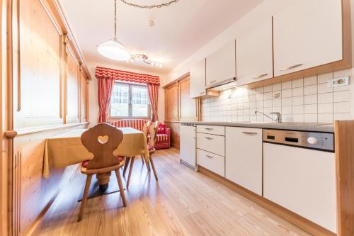 a kitchen with white cabinets and a table and chairs at Garni Hotel Residence Diamant in San Vigilio Di Marebbe